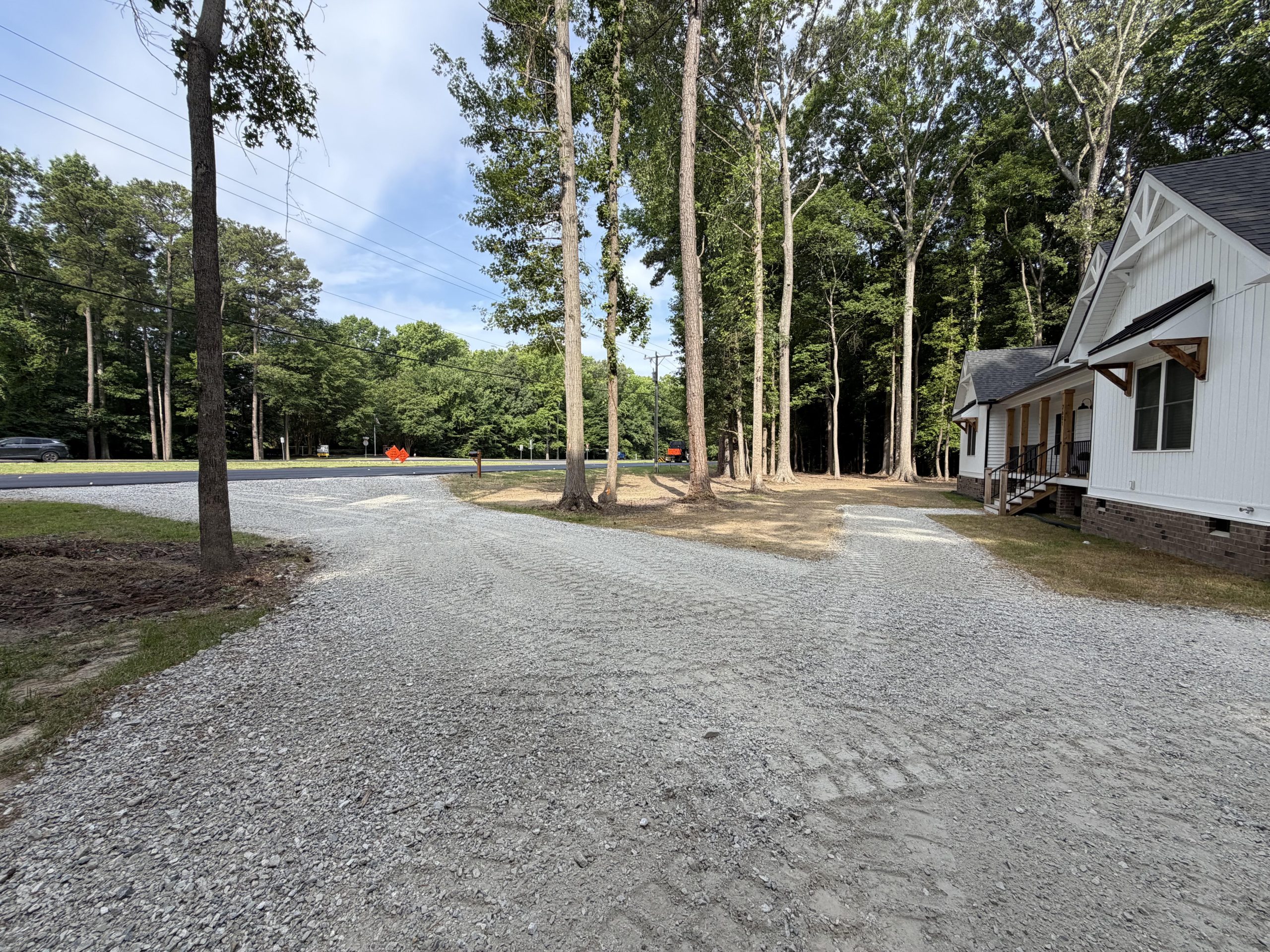 Newly graded gravel driveway lined with trees, installed by Sturtz Contracting